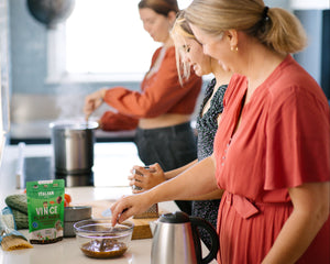 Two women in a kitchen preparing food, with a focus on a bowl of ingredients.
